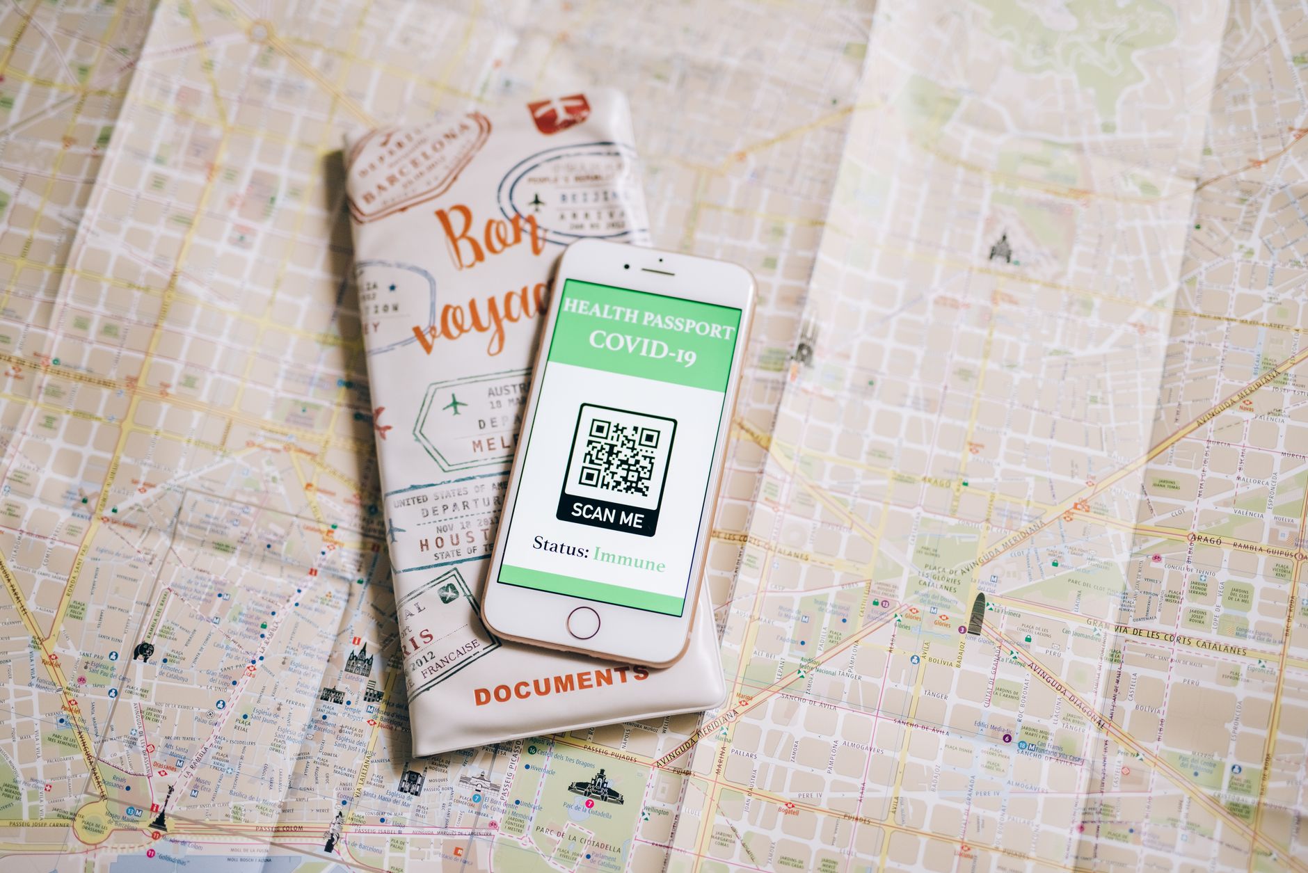 Capture process on LiDAR iPhones: Top view of a smartphone with COVID-19 health passport and travel documents on a map.